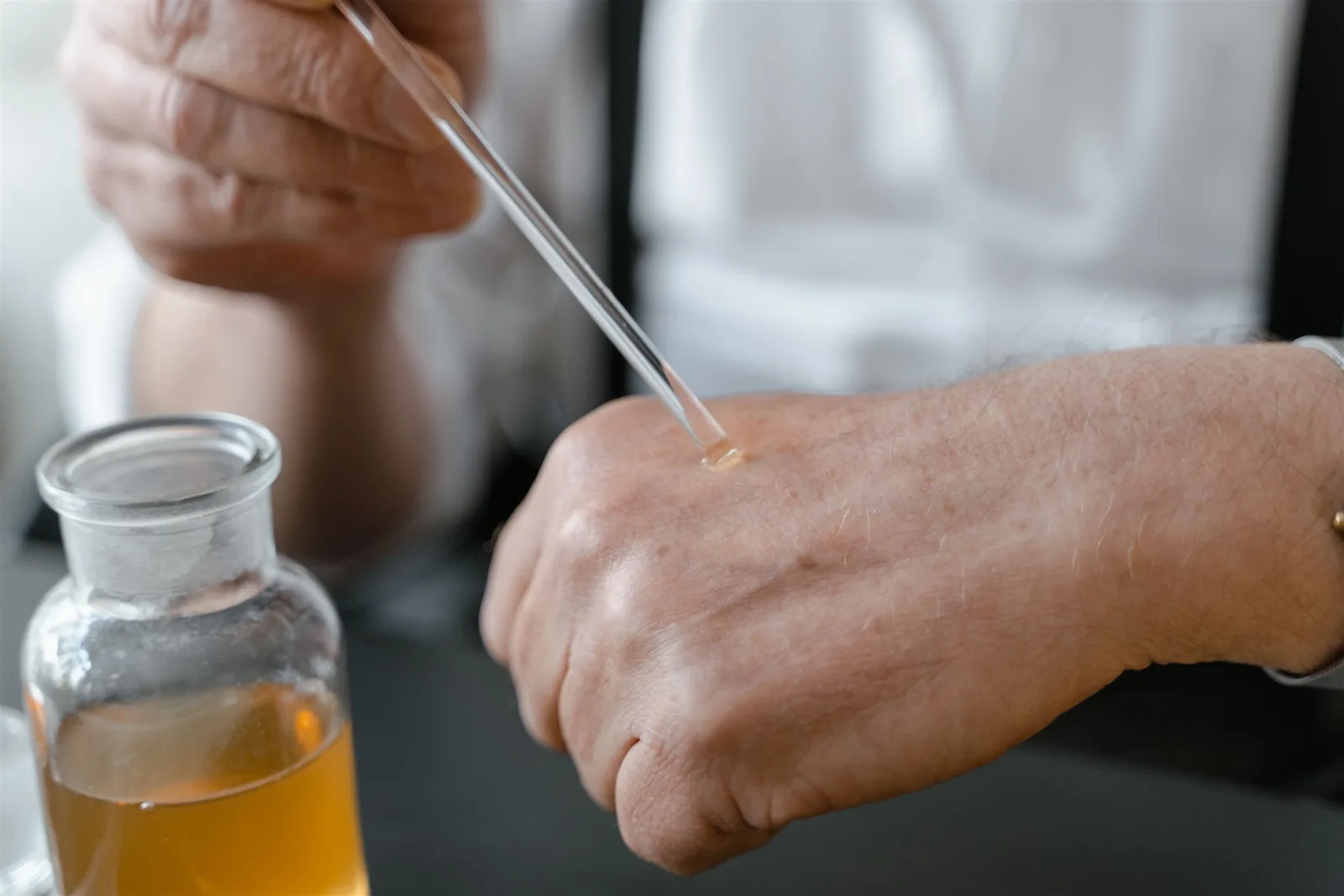 Tangan seseorang mencoba setetes cairan parfum dengan pipet