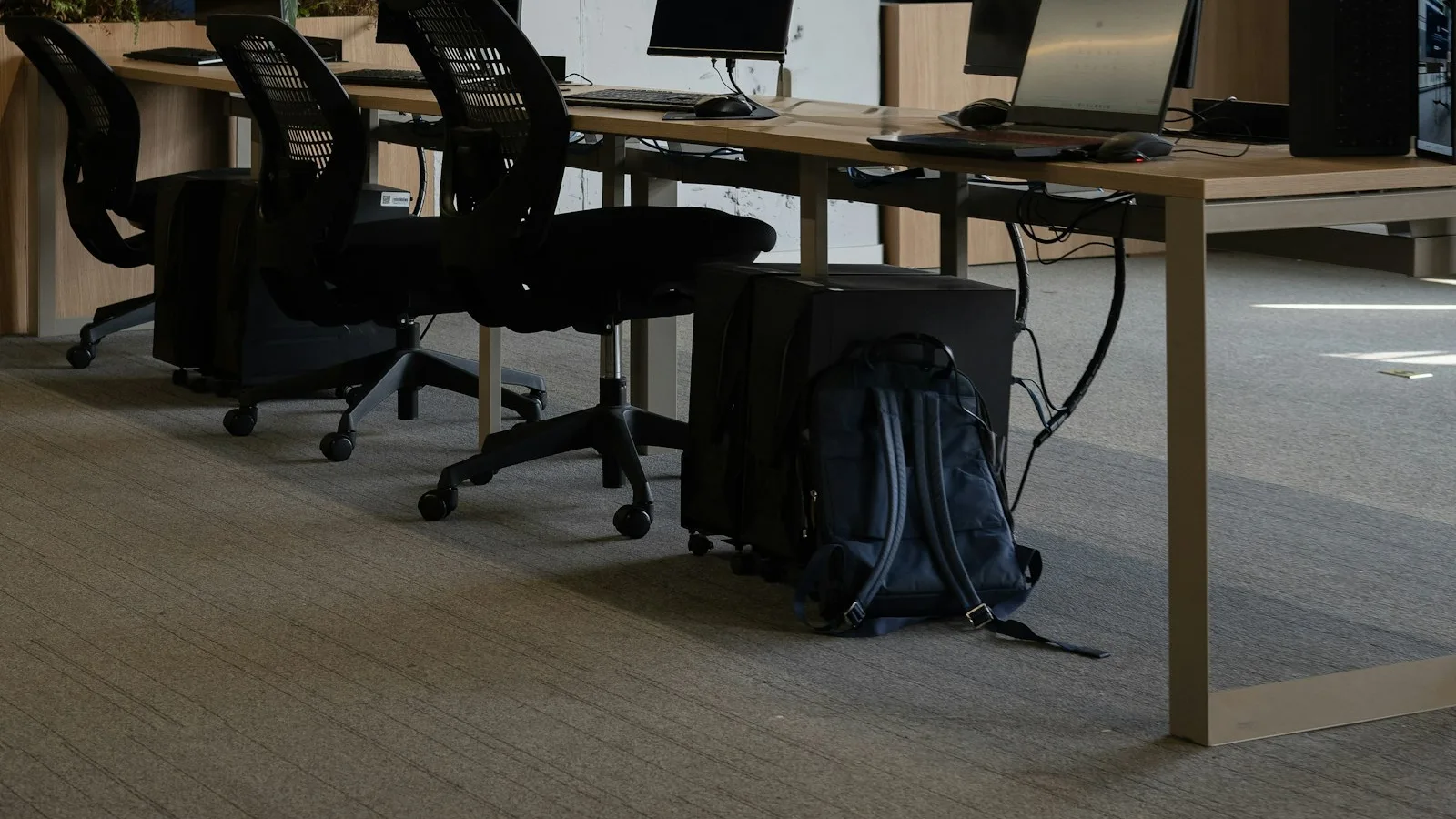 Ruang kerja bersama dengan meja panjang, komputer, dan kursi kantor tanpa orang