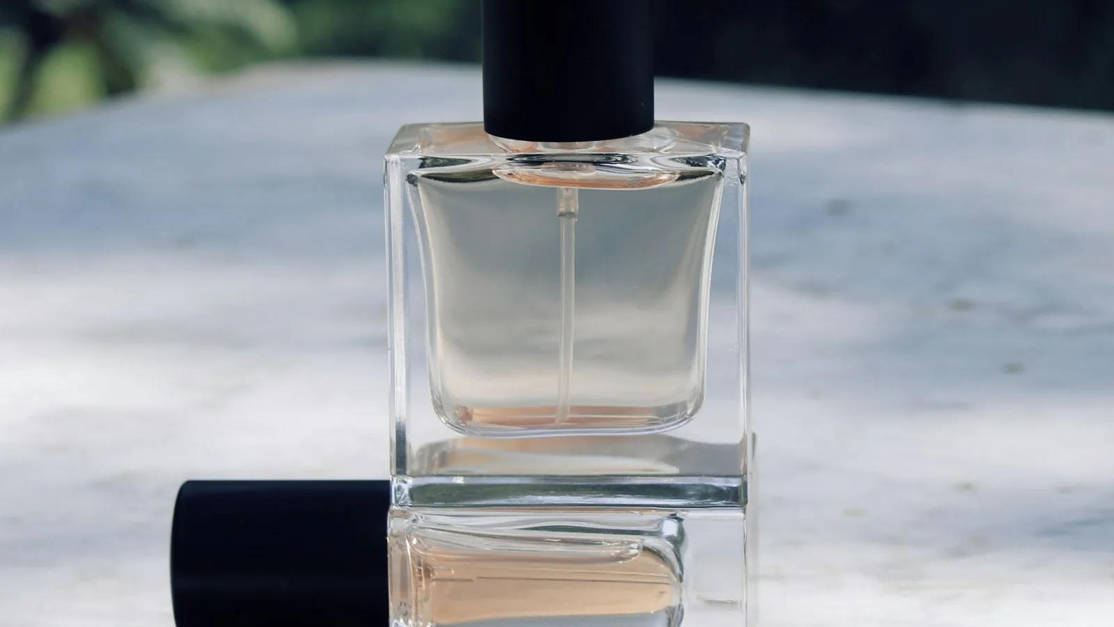 Botol parfum kaca bening tanpa label di atas meja marmer di bawah sinar matahari