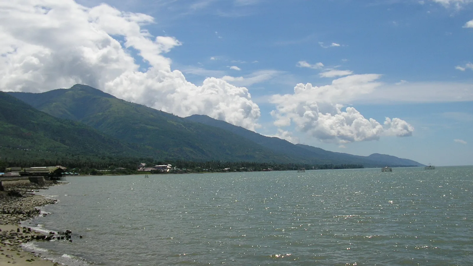 Pesisir Teluk Palu dengan perbukitan hijau dan langit biru berawan